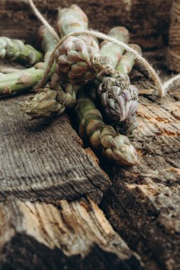 Eski bir ahşap arka planda sicimle bağlanmış taze organik kuşkonmaz sürüsü. Seçici odak