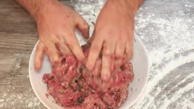 Erkek ellerinin yakın çekimi beyaz kasede kıyma yapar, hamur köftelerini un ile hazırlar.
