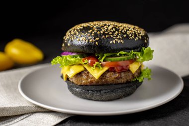 Beef burger with a black bun on the plate