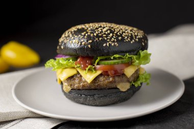 Beef burger with a black bun on the plate