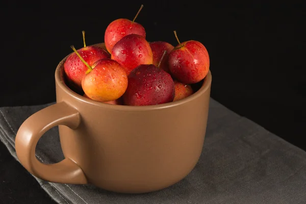 Mini manzanas en taza sobre fondo negro — Foto de Stock