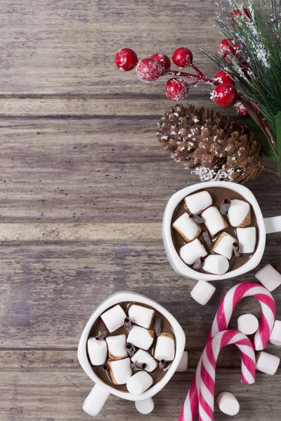 Christmas still life - two cups of hot chocolate with marshmallow, candies and branch of fir with berries — Stock Photo, Image