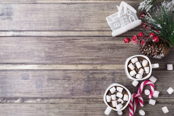 Рождество натюрморт - две чашки горячего шоколада с зефиром, конфеты, игрушечный домик и ветка ели с ягодами — стоковое фото