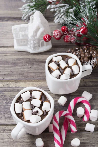 Christmas still life - two cups of hot chocolate with marshmallow, candies, toy house and branch of fir with berries — Stock Photo, Image