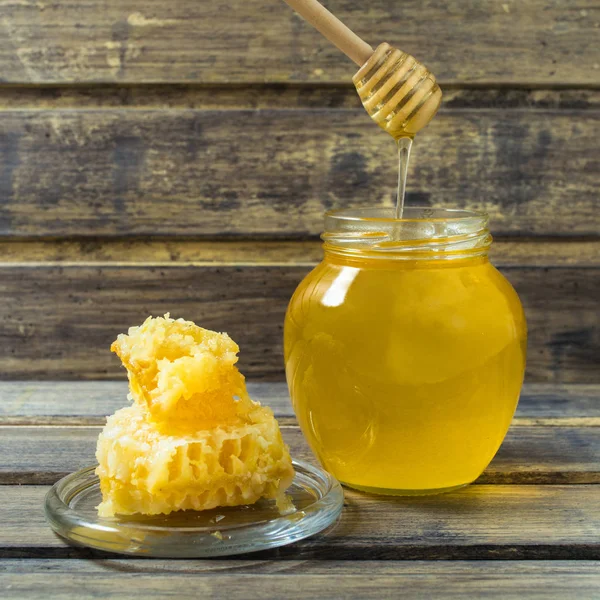 Miele leggero nel barattolo con cucchiaio e favo — Foto Stock