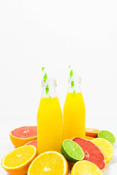 Citrus limonade in de flessen met ingrediënten op de witte houten achtergrond — Stockfoto