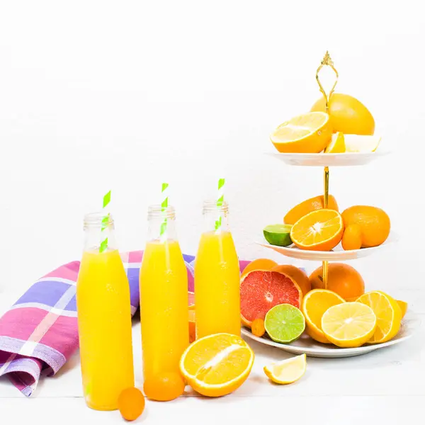 Limun jeruk dalam botol dengan bahan jeruk di atas kios kue — Stok Foto