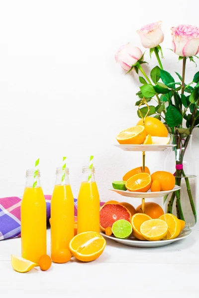 Limun jeruk dalam botol dengan bahan jeruk di atas kios kue — Stok Foto