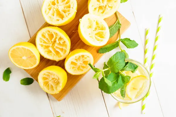 Лимонад с мятой и выжатыми лимонами на борту с соломой — стоковое фото