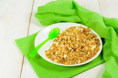 Yeşil plastik kaşık ile beyaz tabakta granola