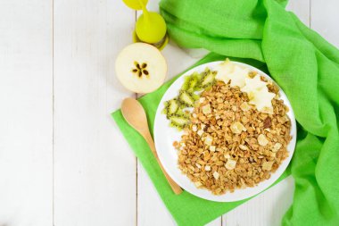 Yeşil plastik kaşık ile beyaz tabakta granola