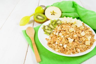 Yeşil plastik kaşık ile beyaz tabakta granola