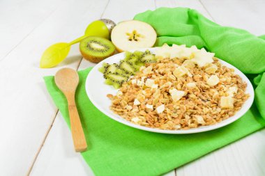 Yeşil plastik kaşık ile beyaz tabakta granola