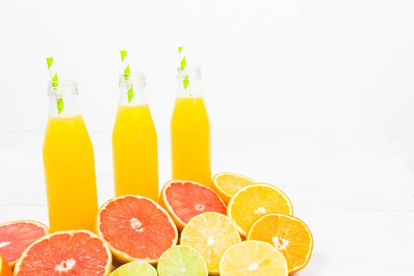 Цитрусовый лимонад в трех бутылках с ингредиентами — стоковое фото