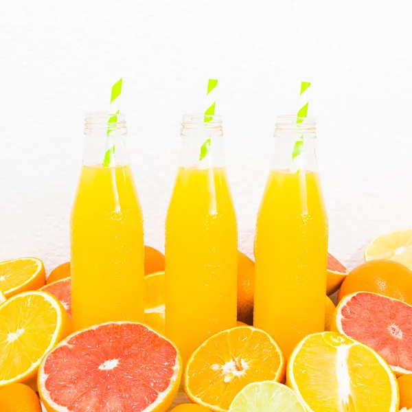 Цитрусовый лимонад в трех бутылках с ингредиентами, квадратный выстрел — стоковое фото