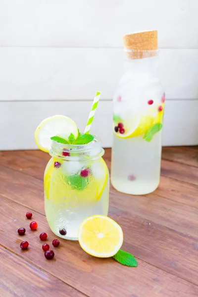 Вода с мятой, лимоном и льдом в кувшине и бутылке — стоковое фото