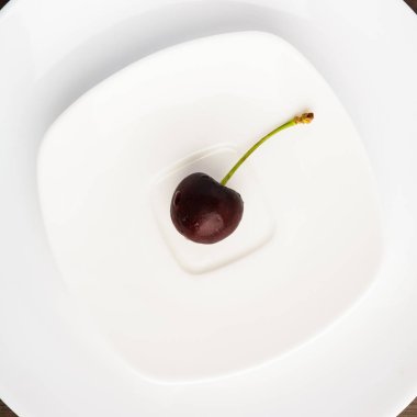 Minimalizm tarzı ahşap backgrou üzerinde beyaz plaka üzerinde bir kiraz