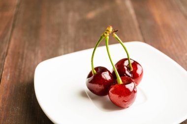 Beyaz plaka üzerinde üç kiraz