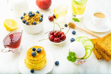 Granola, detoks su, süzme peynir krep, çilek, masada sağlıklı kahvaltı yumurta ve kahve