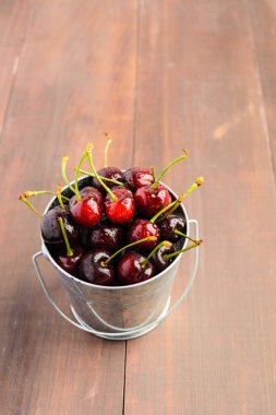 Kiraz ahşap arka plan üzerinde dolu bir kova