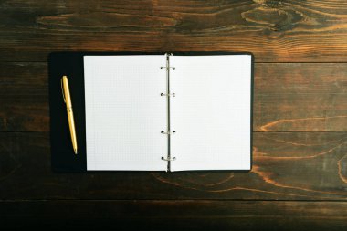 Defter ve kopya alanı ile kahverengi ahşap masa üzerinde altın kalem
