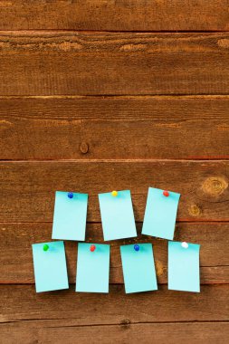 Yedi boş mavi Kağıt ahşap arka plan üzerinde renkli iğne ile