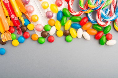 Gri kağıt arka plan üzerinde renkli şekerler