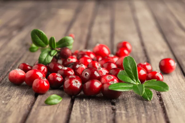 Fresh autumn berries cranberries over brown wooden table with leaves