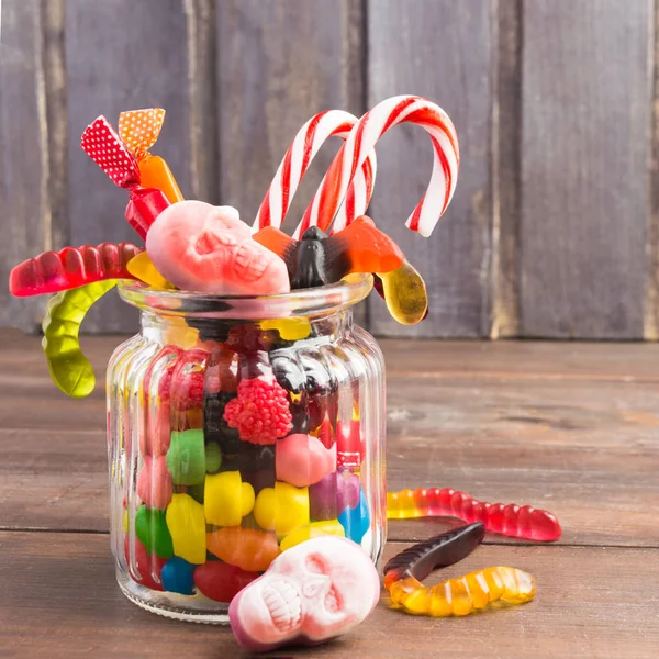 Tarro de vidrio con caramelos para Halloween sobre fondo de madera —  Fotos de Stock