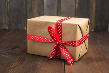 Kraft kağıt ahşap arka plan üzerinde kırmızı kurdele ile hediye