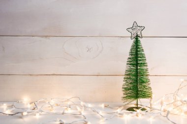 Ahşap arka plan üzerinde garland ile metal yeşil Noel ağacı