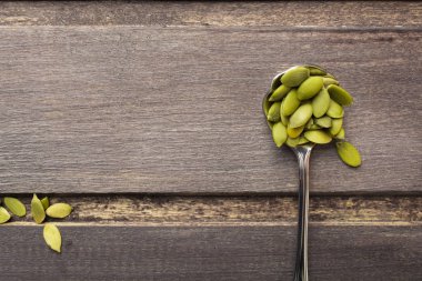 Ahşap masa üzerinde metal kaşık içinde kabak çekirdeği