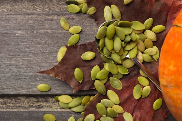 Semillas de calabaza con cuchara y hojas de otoño con espacio para copiar — Foto de Stock