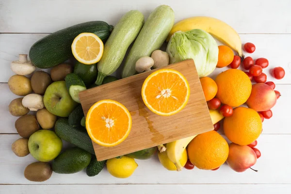 Dos partes de naranja a bordo y otras frutas y verduras — Foto de Stock