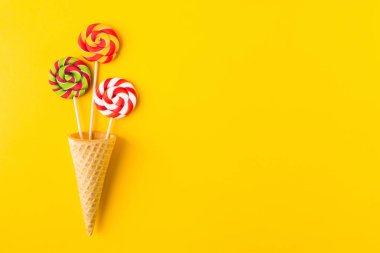 Waffle külahında yapıştırılmış üç renkli şekerleme üzerinde sarı arkaplan ve kopyalama alanı
