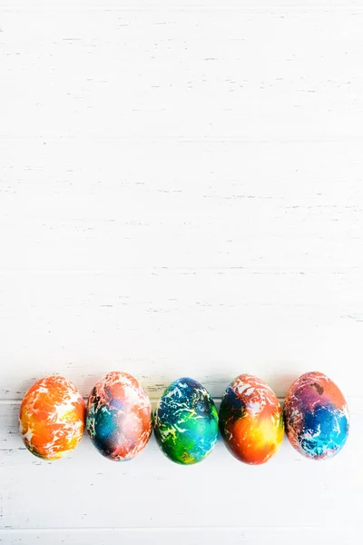 Cinq oeufs colorés de Pâques sur une table en bois blanc avec espace de copie. Maquette. Pose plate. Conception de vacances de printemps — Photo