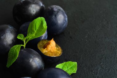 Siyah zemin üzerinde nane yaprakları olan taze organik eriklerin yakın görüntüsü