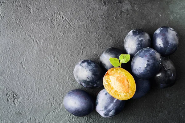 Muchas ciruelas azules saludables orgánicas frescas sobre fondo negro con espacio para copiar — Foto de Stock