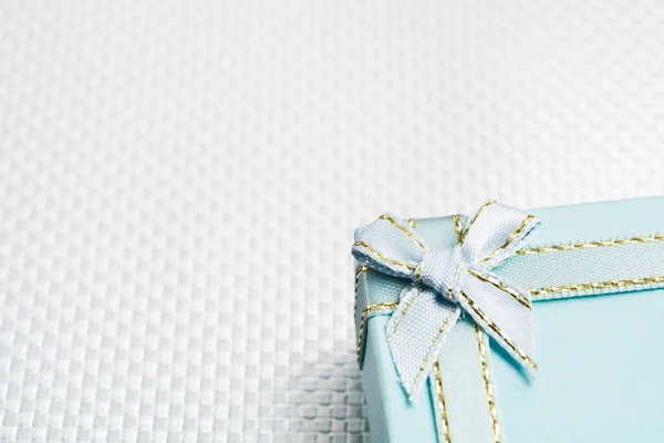 Blue gift box with silver bow over silver textured background
