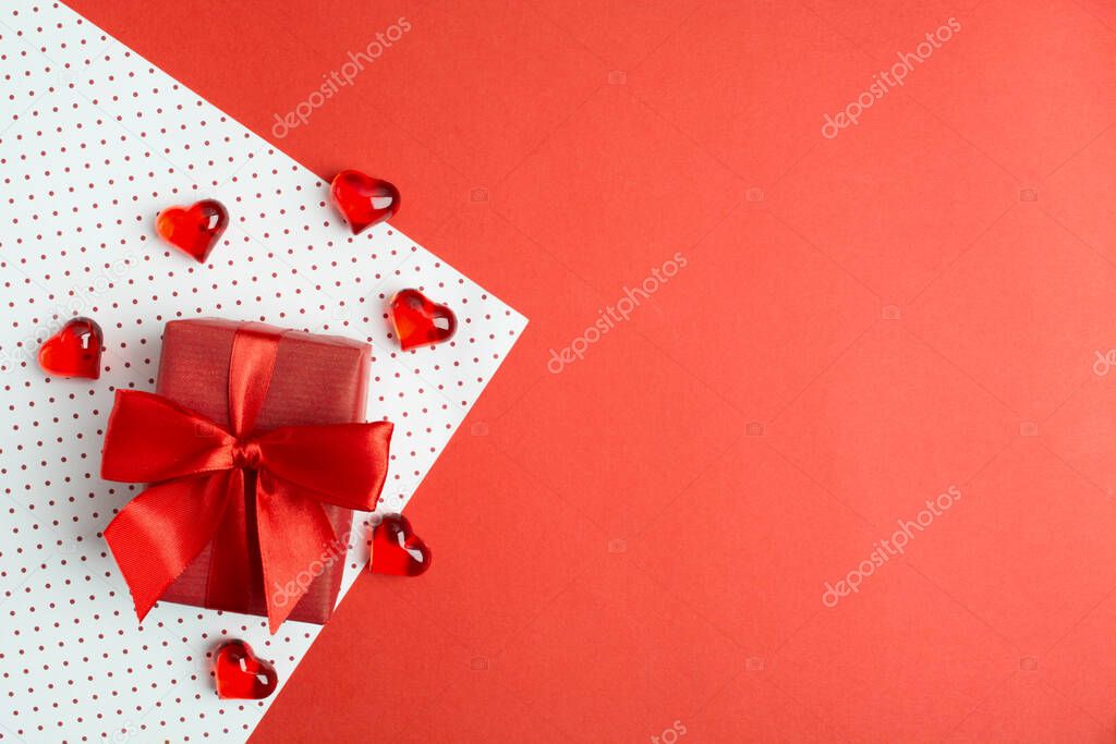 Red gift box with bow on wrapping paper with hearts. Valentine's day's cocncept