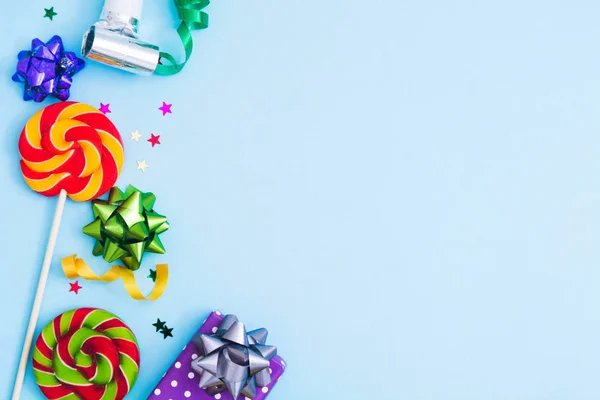Birthday background with candies, bows, confeti and gift box over blue backgroud