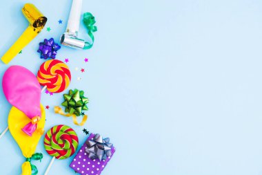 Tatil partisi, karnaval, parti, şenlik satışları. Renkli yayları, balonları, şekerlemeleri, hava üfleyicileri olan doğum günü mavisi arka plan