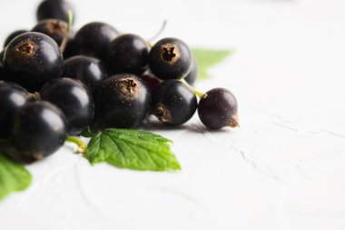 Beyaz desenli arka planda yeşil yapraklı sağlıklı siyah kuş üzümü yığını. Uzayı kopyala Vejetaryen yemeği.