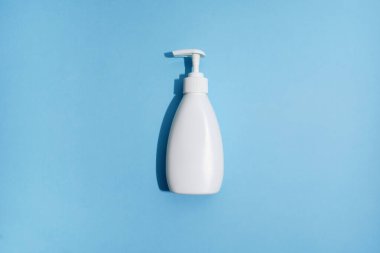 Mavi arka planda beyaz plastik şişe. Modelleme. Düz yatıyordu. Virüsü önlemek için dezenfektan jeli. Covid-19. Sert ışık. Mavi arka plan. Duş jeli ya da liqiud sabunu. Hijyen konsepti. Düz yatıyordu