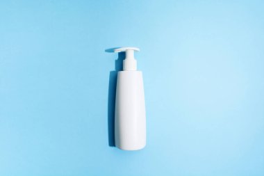 Mavi arka planda beyaz plastik şişe. Modelleme. Düz yatıyordu. Virüsü önlemek için dezenfektan jeli. Covid-19. Sert ışık. Mavi arka plan. Duş jeli ya da liqiud sabunu. Hijyen konsepti. Üst görünüm