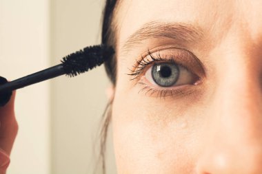 Güzel beyaz kadın kirpiklerini siyah rimelle boyuyor.