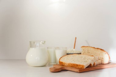 Cam kavanozda süt, masada süzme peynir ve ekmek. Beyaz arkaplan.
