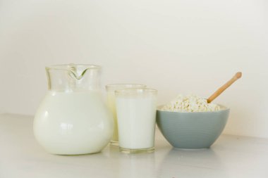 Cam kavanozda süt, masada süzme peynir ve ekmek. Beyaz arkaplan.