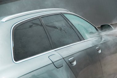 Yüksek basınçlı su kullanarak arabayı temizlemek. Açık hava. 