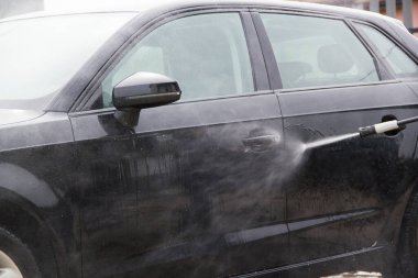 Yüksek basınçlı su kullanarak arabayı temizlemek. Açık hava. 